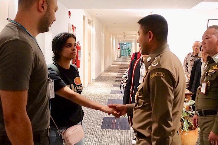 強制送還の恐れから一転、亡命の道が開けたラハフ・ムハンマド・クヌンさん（左から2人目）が、タイ入国管理局職員と握手した。Thai Immigration Bureau / REUTERS