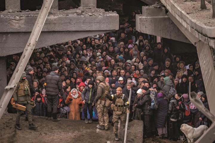 首都キエフ近郊のイルピンで破壊された橋の下を通り、川を渡って避難しようとする人々（3月5日）　AP/AFLO