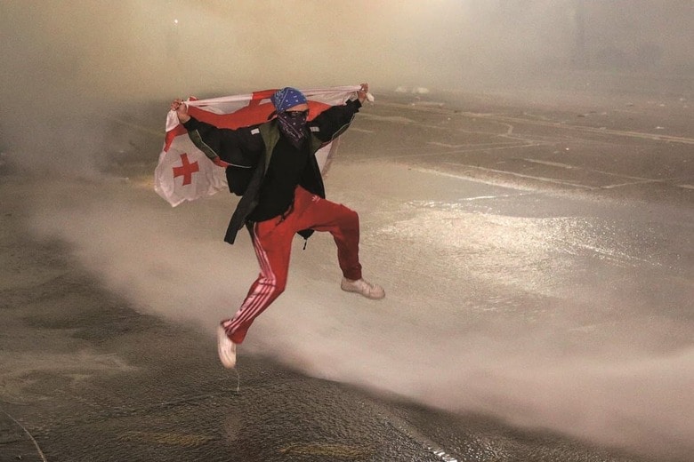 放水をかわすデモ参加者（首都トビリシで）　IRAKLI GEDENIDZE-REUTERS