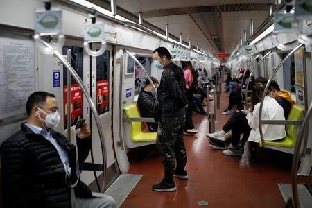 中国共産党機関紙の人民日報は２８日、国民に新型コロナウイルスへの警戒を緩めないよう呼び掛けた。写真は地下鉄車内でマスクをする乗客。２７日北京で撮影（２０２０年　ロイター/Carlos Garcia Rawlins）