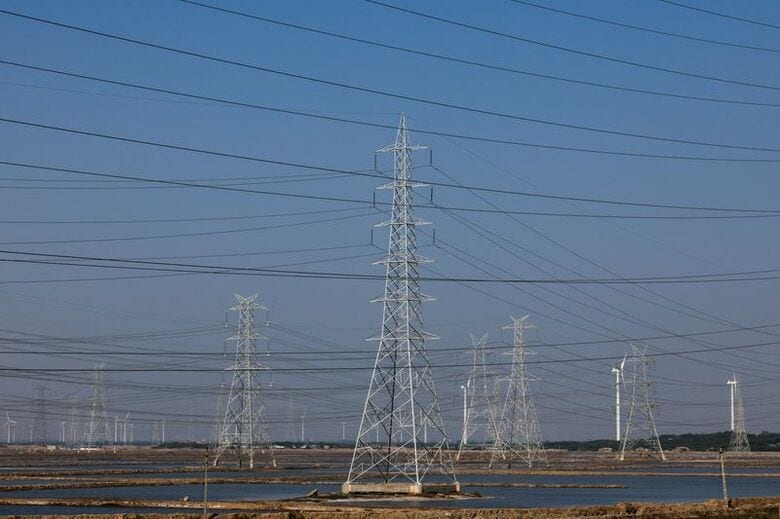 インド西部グジャラート州で高圧送電線の鉄塔と発電用風力タービンが並ぶ様子。2024年11月28日撮影　REUTERS/Amit Dave