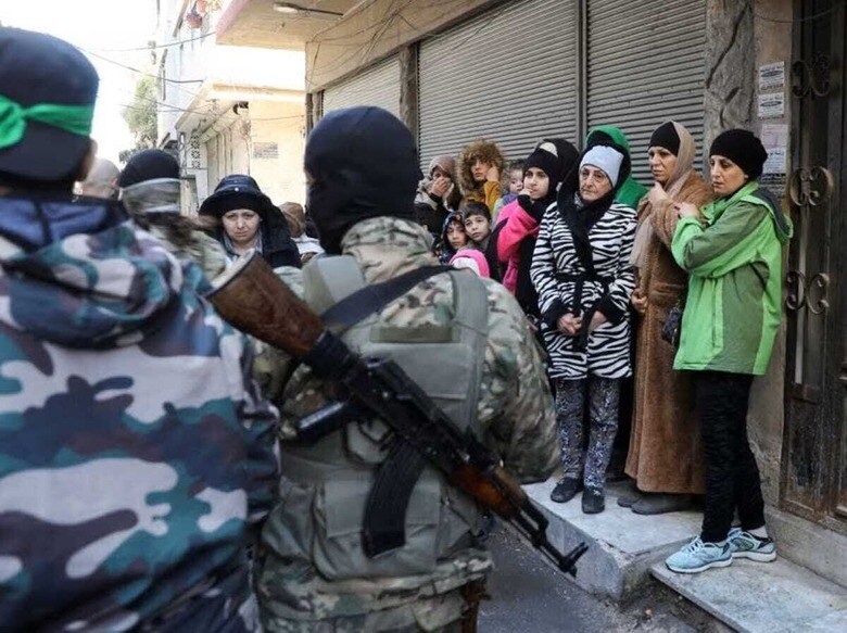 昨年１２月にアサド政権が崩壊したシリアでは、親アサド派や自称「反アサド派」が宗派間の対立をあおり、新生シリアの体制を不安定化させようとデジタル空間で偽情報をまき散らしており、政権移行にとって障害になるとの懸念が広がっている。写真は同国の都市ホムスで、イスラム教スンニ派の武装勢力「シリア解放機構（ＨＴＳ）」によるアサド派残党狩りを見守る人々。１月２日撮影（２０２５年　ロイター/Khalil Ashawi）