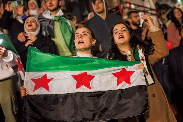今年1月にシリアの首都ダマスカスで行われた元亡命歌手のライブで新しい国旗を掲げる観客　AP/AFLO