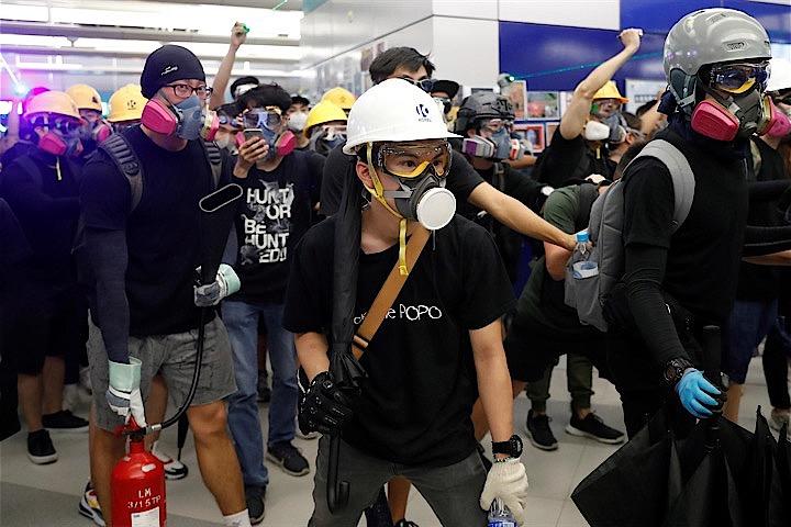 民主化運動に揺れる香港では、平和的な抗議活動と並び、正当な政治表現としての「実力行使」の考えが、次第に主流になりつつある。写真は21日、香港の地下鉄駅で警察と対峙する抗議活動参加者（2019年　ロイター/Tyrone Siu）