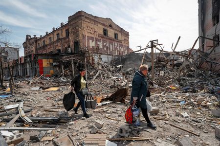 　４月１１日、ウクライナはロシア軍がウクライナ東部の占領に焦点を移しており、近く新たな大規模攻撃を開始するとの見方を示した。写真はマリウポリで１０日、ロシア軍の攻撃で破壊された建物付近を移動する市民（２０２２年　ロイター/Alexander Ermochenko）