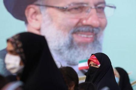 イラン大統領選挙で反米・保守強硬派のライシ司法府代表が当選した。写真はライシ師のポスターの周りに集まる支持者。６月１９日、テヘランで撮影（２０２１年　Majid Asgaripour/WANA (West Asia News Agency) via REUTERS）