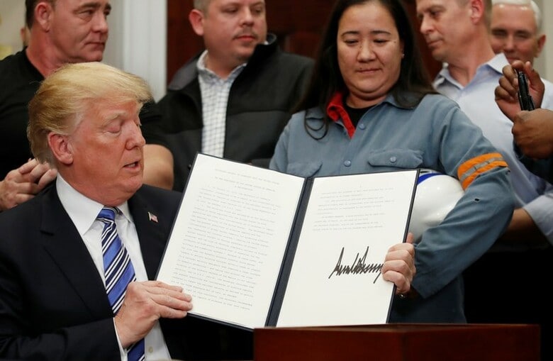 ３月８日、トランプ米大統領は記者会見で、鉄鋼とアルミニウムにそれぞれ２５％と１０％の関税を課す輸入制限を実施することを正式に発表した。ホワイトハウスで輸入制限を実施する文書に署名したトランプ氏（２０１８年　ロイター/Leah Millis）