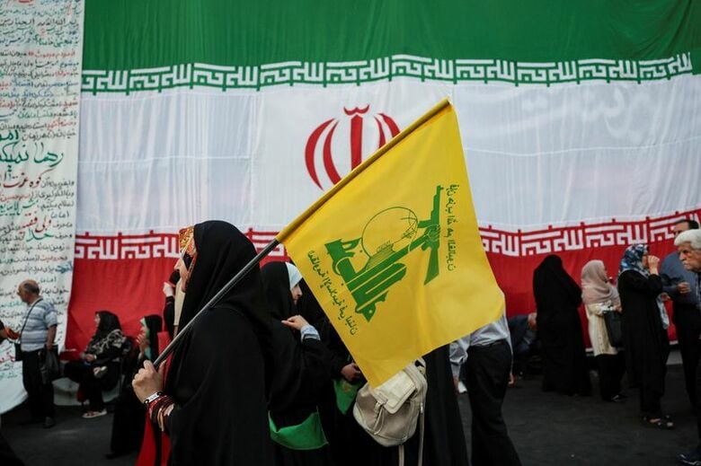 イランの最高指導者モジタバ・ハメネイ師を支持する集会で、レバノンのイ​スラム教シーア派組織ヒズボラの旗を持つ女性。テヘランで４日撮影の提供写真。Majid Asgaripour/WANA (West Asia News Agency) via REUTERS