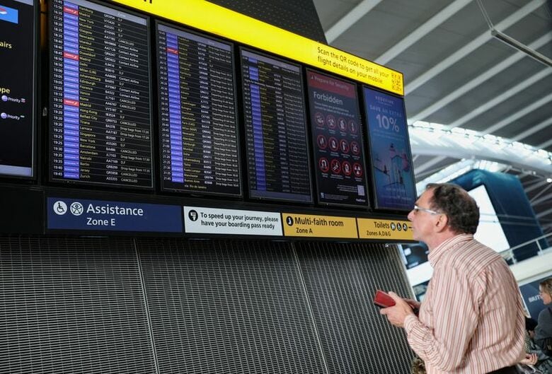 ロンドンのヒースロー空港第5ターミナルで、欠航便を表示する出発案内板を見る乗客。9月8日撮影。REUTERS/Isabel Infantes