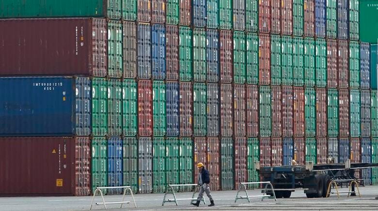 都内の港でコンテナの横を歩く作業員。2012年3月22日撮影。REUTERS/Toru Hanai