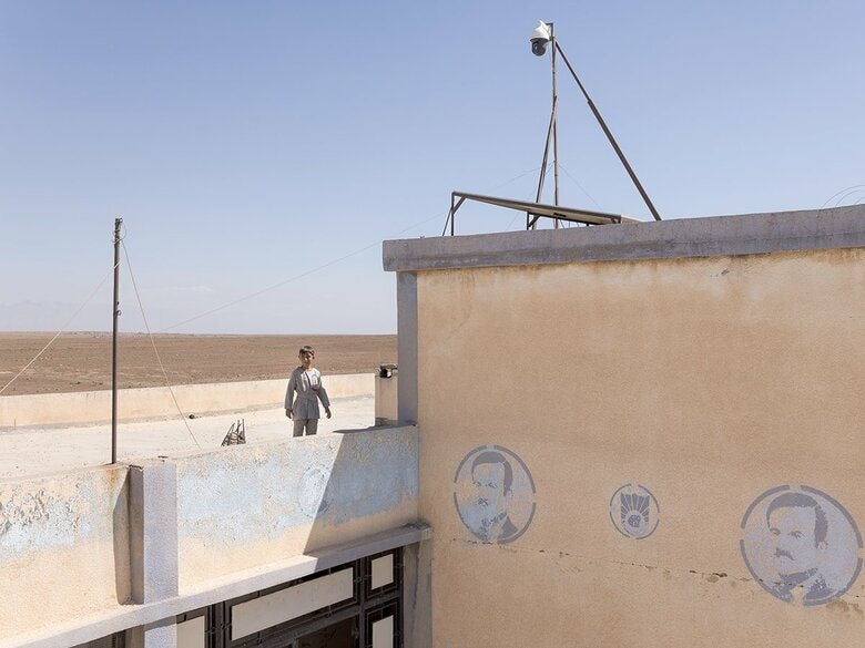 ジャルディ村の学校の屋上に立つ少年。シリア内戦で破壊された後の2013年、住民たちは村の中心部に共同の庭園兼菜園を整備した。収穫した農産物は近隣の市場で販売され、その収益は住民の共同基金に充てられている