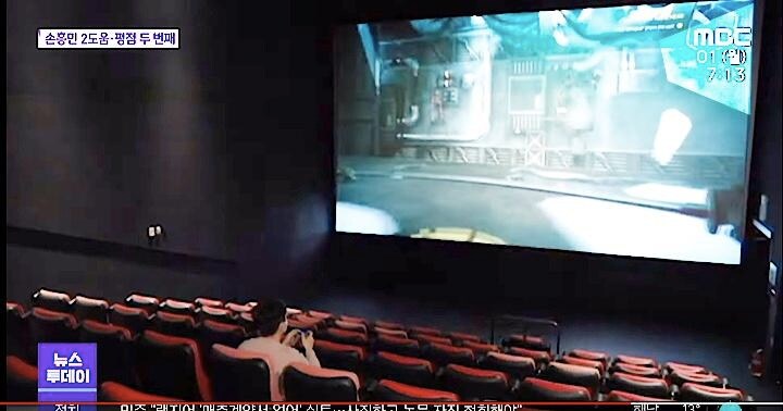 映画館のスクリーンの前にはゲームのコントローラーをもった男性がひとり。韓国ではさまざまな形で映画館が生き残りを模索している。MBCNEWS / YouTube