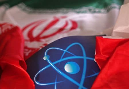３月１４日、中国、イラン、ロシアの３カ国がイランの核問題を巡る次官級会合を北京で開いた。国営の中国中央テレビ（ＣＣＴＶ）が報じた。写真は原子記号とイラン国旗。２０２２年９月撮影（２０２５年　ロイター/Dado Ruvic）