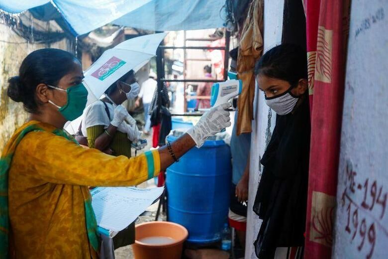 インドの新型コロナウイルス感染症による死者数は17日、5万人を突破、感染者数は265万人近くとなった。ムンバイのスラム街で体温を測るボランティア、17日撮影。(2020年　ロイター/Francis Mascarenhas)