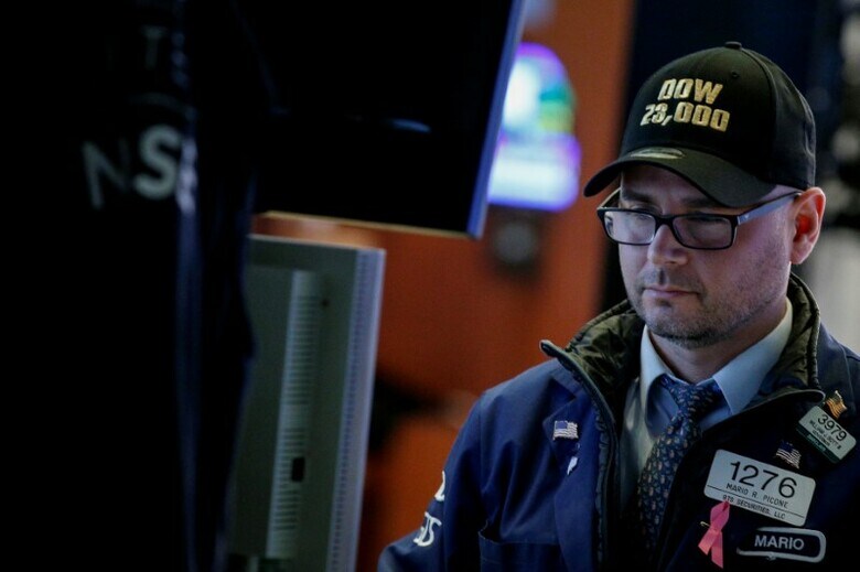 １０月１９日、１９８７年の株価大暴落から３０年を迎え、米国株は史上最高値を記録した。健全な企業業績と経済成長にもかかわらず、高騰するバリュエーションは、価格調整が迫っていることを意味するのではないかと投資家は危惧している。写真はダウ平均が２万３０００ドルを超えた記念の帽子をかぶるトレーダー。ニューヨーク証券取引所で１７日撮影（２０１７年　ロイター/Brendan McDermid）