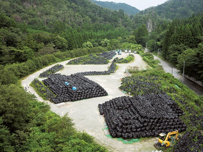 除染によって出た汚染土などを詰めた黒いバッグが、中間貯蔵施設に次々と運ばれていく（浪江町、23年）