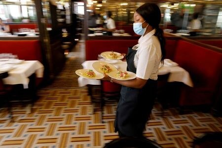 FILE PHOTO: A waiter serves dishes in a dining room at Au Petit Riche restaurant in Paris as cafes, bars and restaurants reopen indoor dining rooms in France, June 9, 2021. REUTERS/Pascal Rossignol