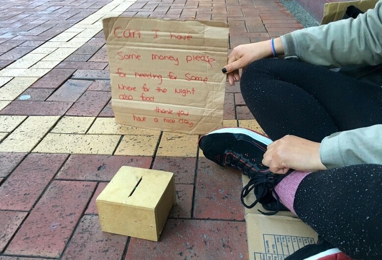 ５月２１日、酪農を主力とするニュージーランド経済は、ここ数年、富裕な先進諸国の羨望の的だった。だが、好景気にもかかわらず、数万人の住民が、車中や店舗の出入口、路地などで寝起きする生活を強いられている。写真は物乞いする女性のホームレス。ウェリントン中心部で１５日撮影（２０１８年　ロイター/Jonathan Barrett）