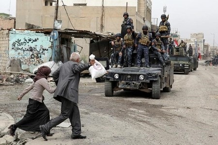 　４月１６日、イラクの警察当局は過激派組織「イスラム国」（ＩＳ）が北部モスルでの戦闘で化学兵器を使用したとして非難した。だが、これにより軍の進めるモスル西部奪還作戦が妨げられることはないという。写真はモスル西部をパトロールするイラクの警察部隊と励ましの声をかける市民（２０１７年　ロイター／Marko Djurica）