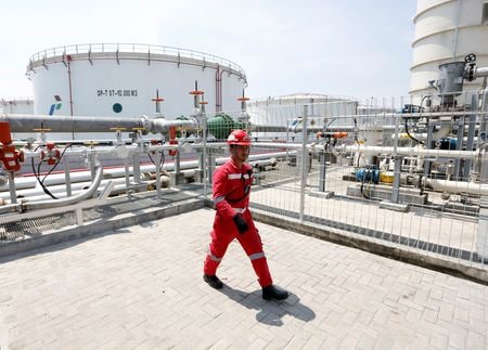 インドネシアの国有エネルギー会社プルタミナは７日、中部スマトラ地方での二酸化炭素回収・有効利用・貯留（ＣＣＵＳ）の商業化に向けた共同調査契約を三井物産と締結したと発表した。写真はプルタミナの貯蔵タンクと作業員。ジャカルタで２０１８年撮影。（2022年 ロイター/Willy Kurniawan）