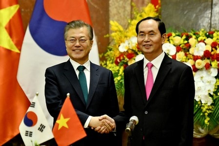 　３月２３日、ベトナムと韓国は、２国間の貿易額を２０２０年までに昨年の５０％増の１０００億ドルに引き上げることで合意した。写真は握手を交わす韓国の文在寅（ムン・ジェイン）大統領（左）とベトナムのチャン・ダイ・クアン国家主席。ハノイで撮影（２０１８年　ロイター）