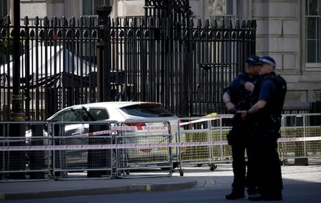 英ロンドン警察は２５日、スナク首相官邸のあるダウニング街の正門に車が衝突したと発表した。運転手の男は危険運転の疑いで逮捕されたという。写真は５月２５日、英首相官邸のあるダウニング街の正門に衝突した車の前に立つ警察官（２０２３年　ロイター／Henry Nicholls）