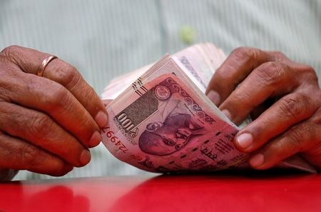 ４月１日、 インドのモディ首相はインド準備銀行（中央銀行）の設立９０周年を記念する式典で、中銀は国の経済成長を優先するとともに、ルピーをより利用しやすく、世界的に受け入れられるようにする必要があると述べた。写真は２０１８年８月、ムンバイの商店でルピー紙幣を扱う人（２０２４年　ロイター/Francis Mascarenhas）
