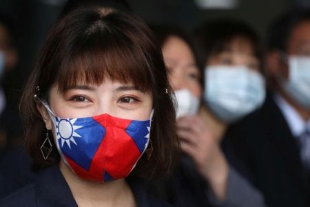 ３月３０日、台湾の外交部（外務省）は、新型コロナウイルスの感染例や予防措置の詳細について台湾が世界保健機関（ＷＨＯ）に提供した情報が他の加盟国に共有されていないと批判した。写真は台湾・桃園の工場で、台湾旗柄のマスクをつけた女性（２０２０年　ロイター/Ann Wang）