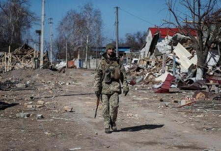 ウクライナ南東部マリウポリでは、前日にロシア側が突き付けた降伏の要求をウクライナ側が拒否したのに続き、ロシア軍が激しい空爆を実施し、市街戦も繰り広げられた。写真は２１日、キエフ州東部で破壊された村を歩くウクライナ軍兵士（２０２２年　ロイター／Gleb Garanich）