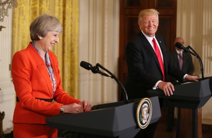２月２０日、トランプ米大統領（写真右）の英国訪問に対する国民の反発が高まるなか、英政府は大統領の公式訪問を予定通り実施する方針を示した。左はメイ英首相、ワシントンで１月撮影（２０１７年　ロイター/Carlos Barria）