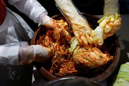 　９月３日、韓国料理に欠かせないキムチが、気候変動の脅威にさらされている。写真はキムチを仕込むイ・ハユンさんら。８月、韓国・南楊州市で撮影（２０２４年　ロイター/Kim Soo-hyeon）