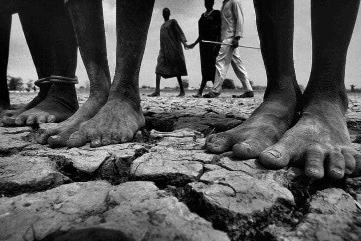 干ばつでひび割れた大地に立って配給を待つ女性たち（南スーダン・チュリル村、2003年6月） Noboru Hashimoto