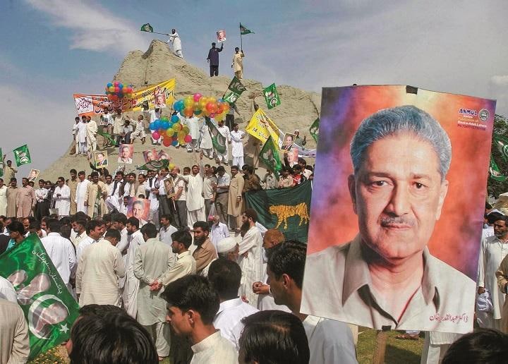 カーンの顔写真を掲げてパキスタン初の核実験10周年を祝う人々（2008年）　FAISAL MAHMOODｰREUTERS
