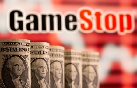 ３月８日、米ゲーム販売ゲームストップの株式が、取引で４０％超値を上げた。その他｢ミーム株｣（ネットの情報拡散で取引される銘柄）も上昇。写真は米ドル紙幣とゲームストップのロゴ。２月撮影（２０２１年　ロイター/Dado Ruvic）