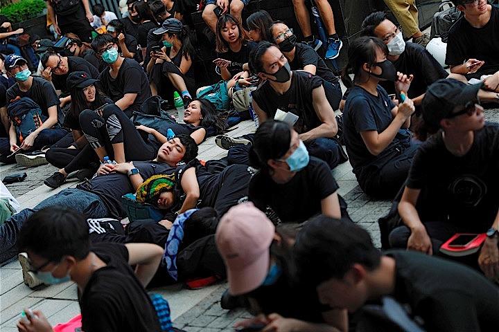 中国本土への刑事事件の容疑者引き渡しを可能にする逃亡犯条例改正案を巡り、反対派らが設定した撤回期限の21日となる中、数百人が市内をデモ行進した。写真は立法会前で休憩するデモ参加者。香港で撮影（2019年　ロイター／Tyrone Siu）
