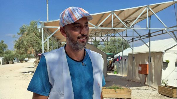 文化的仲介者イハブ。後ろは難民キャンプの仮設住宅。