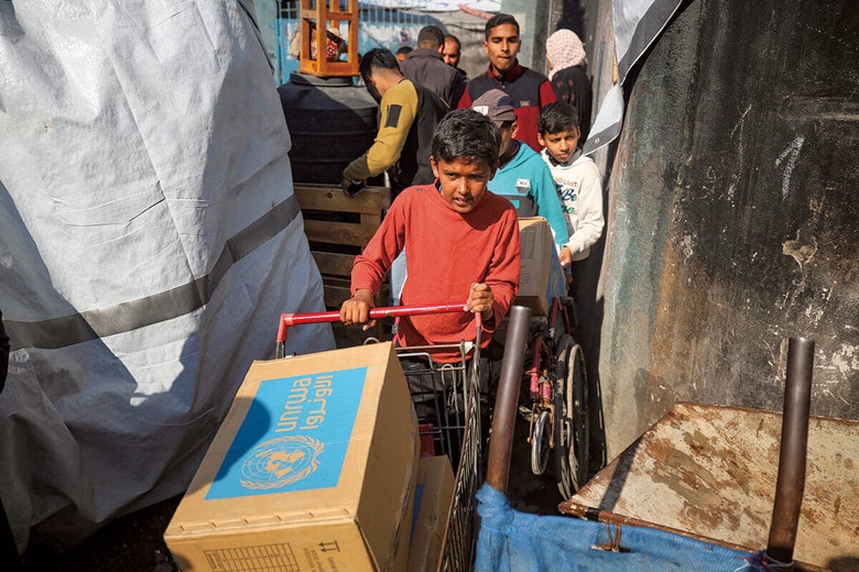 UNRWAが届けた食糧を運ぶパレスチナの人々（1月29日、ガザ地区）　MAJDI FATHIｰNURPHOTOｰREUTERS