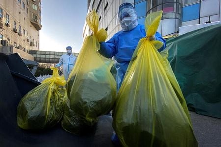 　関係筋によると、中国政府は早ければ７日にも１０項目の新たな新型コロナウイルス管理対策を発表する可能性がある。 写真は医療用廃棄物が入った袋を動かす防護服姿の作業員。北京で５日撮影（２０２２年　ロイター／Thomas Peter）