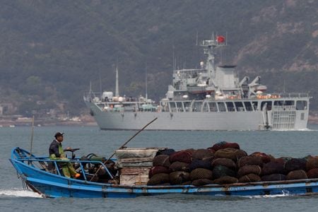 　８月２６日、中国は昨年、西太平洋地域における軍事演習に国防予算の７％に当たる約１５０億ドルを支出した。台湾軍の内部分析報告の内容をロイターが確認して分かった。写真は軍事演習の際、中国の軍艦の横を通り過ぎる漁船。中国の福建省福州沖で昨年４月撮影（２０２４　ロイター／Thomas Peter）