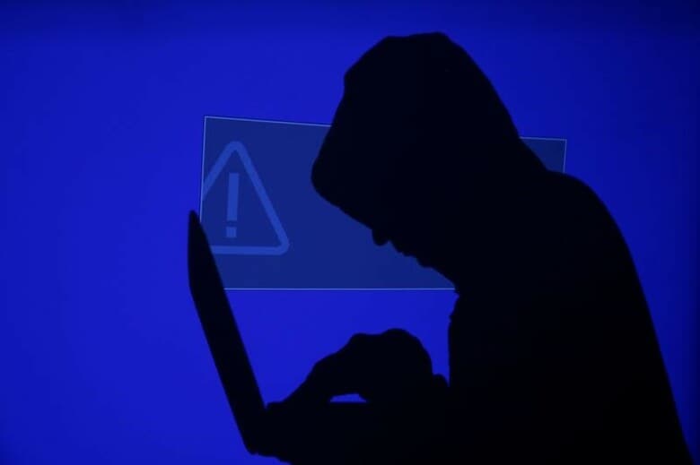 ５月１４日、米国以外の多くの企業は、世界各地で発生している大規模サイバー攻撃への備えが欠けており、甚大な損害を被る可能性があると、複数の保険会社が明らかにした。写真は、ノートパソコンを持つフードをかぶった人。ワルシャワで１３日撮影（２０１７年　ロイター/Kacper Pempel）