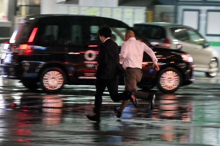 台風19号のなか、東京品川の交差点を走って渡るサラリーマン　Kevin Coombs- REUTERS