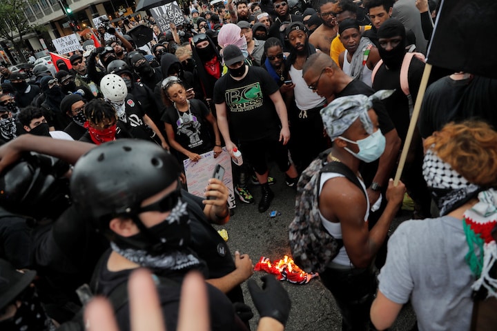 シャーロッツビル事件から1年、白人至上主義者の記念集会に抗議して集まったアンティファのメンバー。黒人差別の象徴である南軍旗を燃やす（2月18日、首都ワシントン）　Lucas Jackson-REUTERS