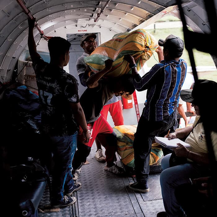 アマゾン地域の川で捕った魚が入った70キロの袋を航空便に積み込むバランコミナスの漁師。住民にとっては貴重な収入源だ