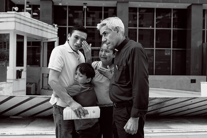 毎週、移民たちの審問に同行する活動を続けているファビアン・アリアス神父（右）。連行を免れた父に抱き付き子供が涙を流す