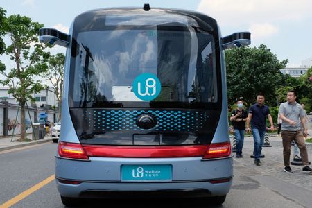 2021年5月、中国広東省広州市にあるウィーライドのオフィス付近で、自動運転バスの前を歩く人々。REUTERS/Yilei Sun