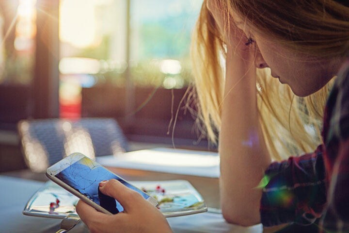 女子中高生は友人から嫌われまいと常にスマホの画面に見入っている　praetorianphoto/iStock.　