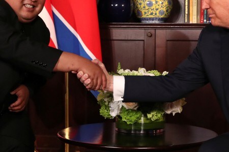 　６月１２日、シンガポールで開かれた史上初の米朝首脳会談で、トランプ米大統領（右）と北朝鮮の金正恩・朝鮮労働党委員長（左）は、初めて顔を合わせた瞬間、互いにその場を支配しようとしたと、専門家は指摘する。同国セントーサ島のカペラ・ホテルで撮影（２０１８年　ロイター/Jonathan Ernst）