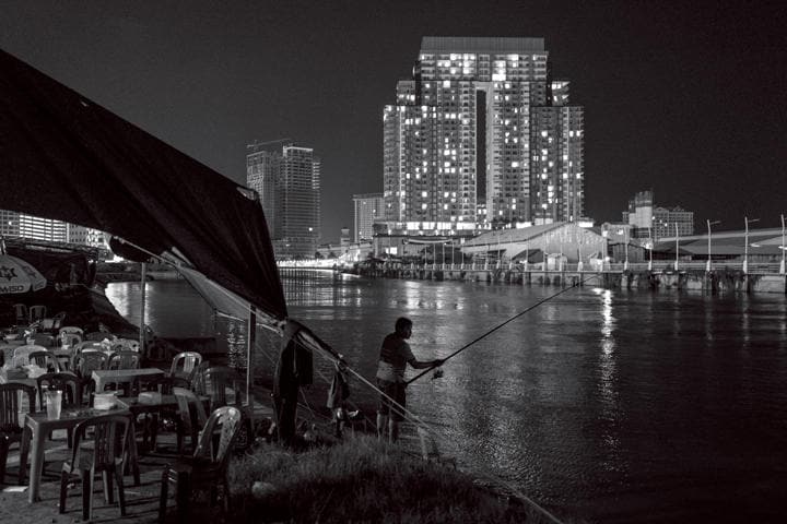 開発が進む首都プノンペンのコーピッチ地区。周辺の高層ビルはどれも過去10年以内に建てられたもので、川岸には開発地区から立ち退かされた貧困層が暮らす