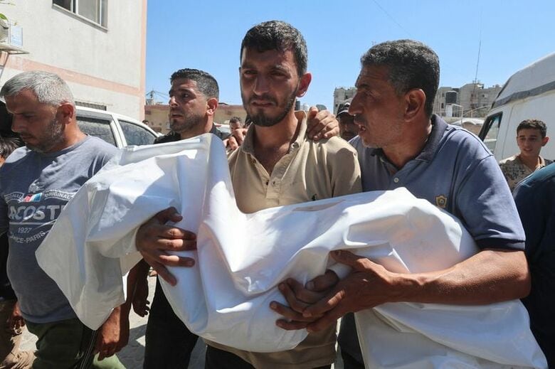 イスラエル軍による攻撃で死亡した６歳の少女の遺体を運ぶ男性。ガザ南部ハンユニスで２５日撮影。REUTERS/Ramadan Abed