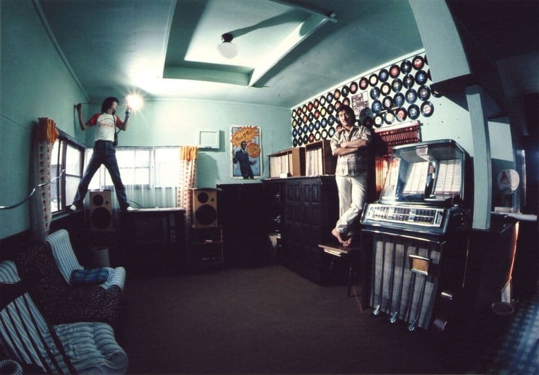 福生45スタジオ隣のミーティング棟にて。壁のドーナツ盤とお気に入り盤収納のジュークボックスが光る。貼ってあるポスターはLP『Buddy Holly Box』の付録だったもの。©THE NIAGARA ENTERPRISES INC.